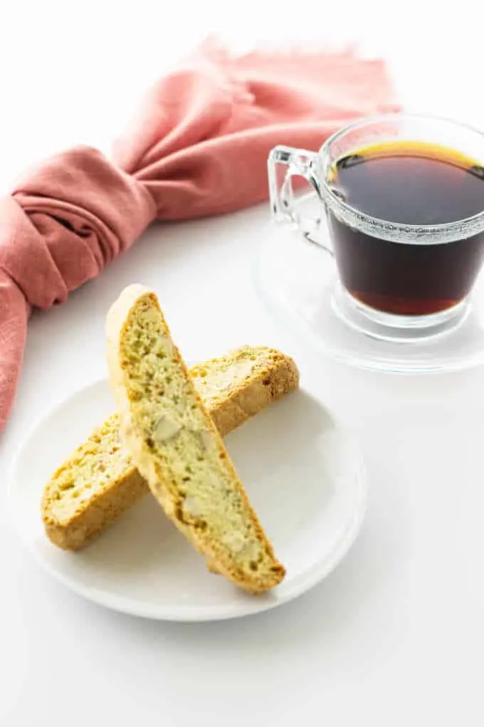 a plate of almond biscotti with a cup of coffee