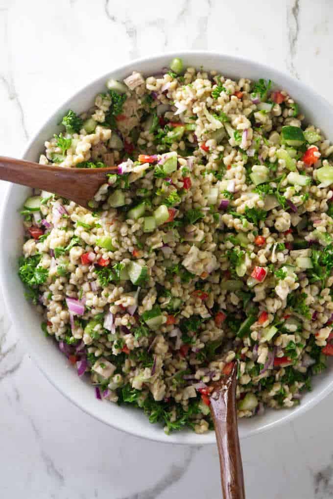 tossing the ingredients for chicken barley salad