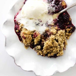 serving dish of blackberry crumble with vanilla ice cream