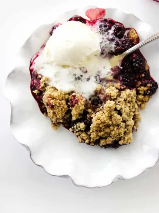 serving dish of blackberry crumble with vanilla ice cream