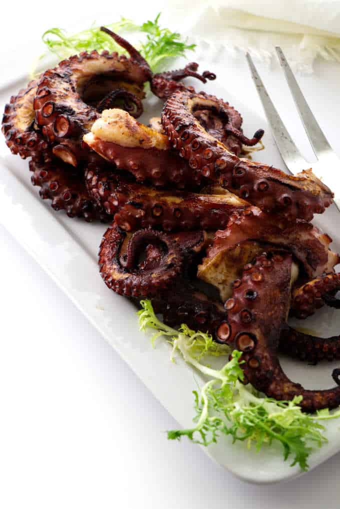 Overhead photo of grilled octopus legs on plate with serving fork