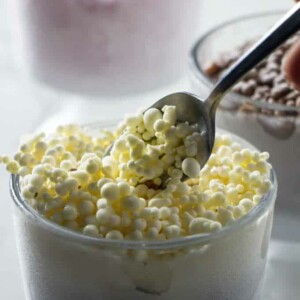 Vanilla dippin dots in a clear glass with a spoon.