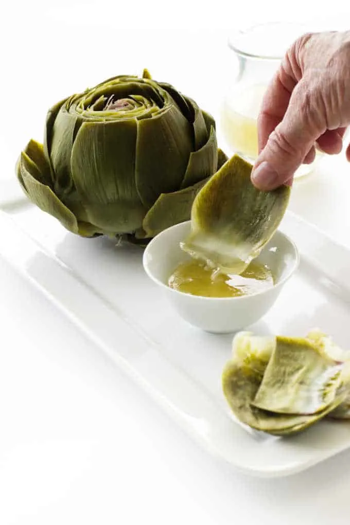 A steamed artichoke with dipping sauce