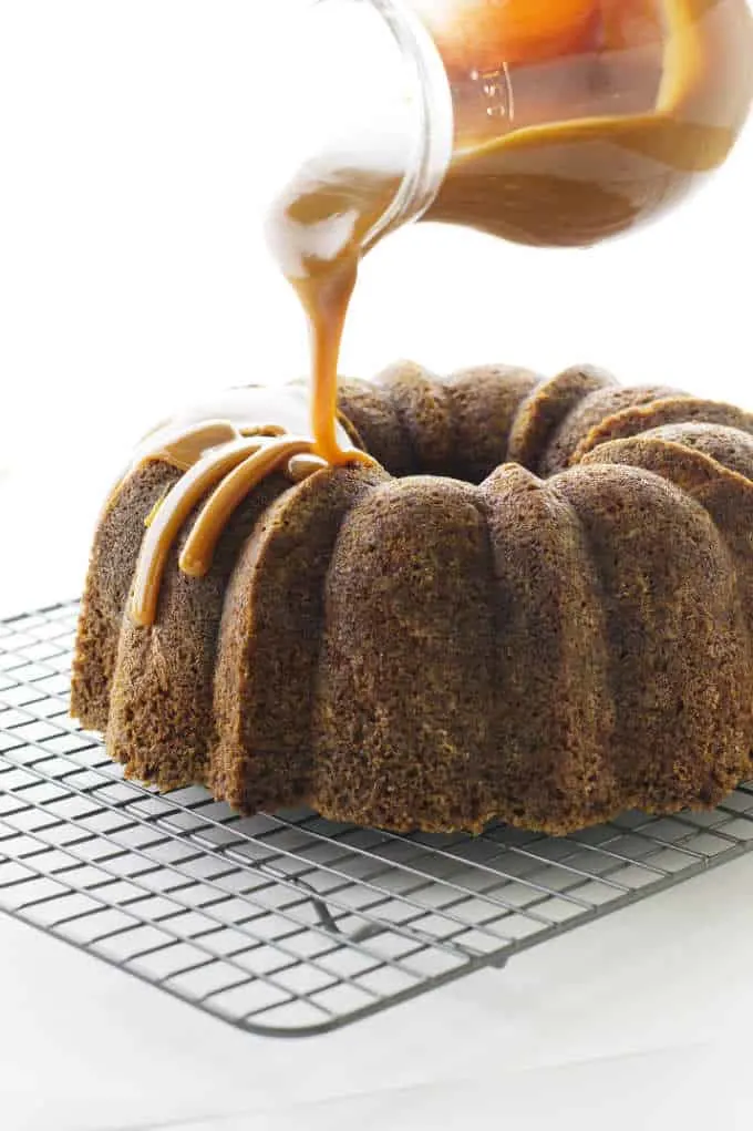 A Bundt Cake made with apples and topped with Caramel Sauce being poured on.