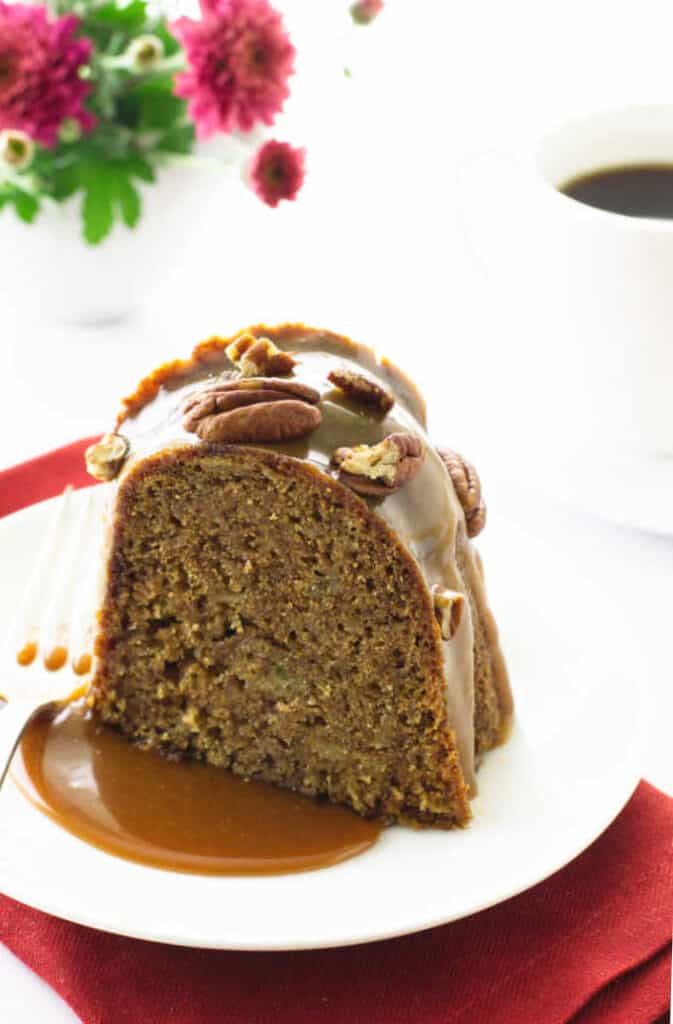 A slice of caramel apple cake on plate with fork.