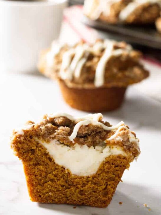 pumpkin muffin sliced open and showing cheesecake stuffing in the center