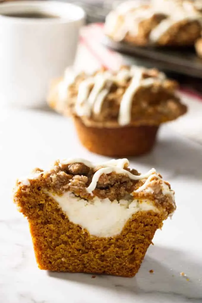 pumpkin muffin sliced open and showing cheesecake stuffing in the center