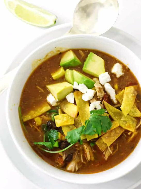 Chicken tortilla soup in a serving bowl next to a spoon.