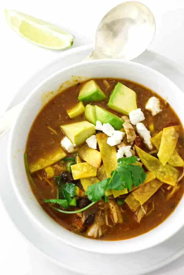 Chicken tortilla soup in a serving bowl next to a spoon.