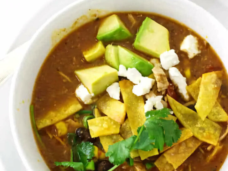 Chicken tortilla soup in a serving bowl next to a spoon.