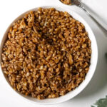 Instant pot farro grains in a bowl next to a spoon.