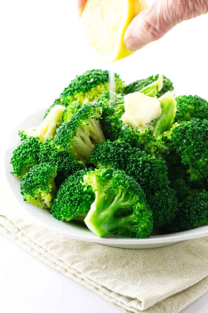 squeezing fresh lemon on steamed broccoli