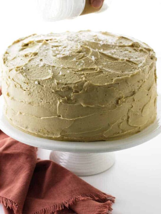 Cake on pedestal with salt being sprinkled on top.