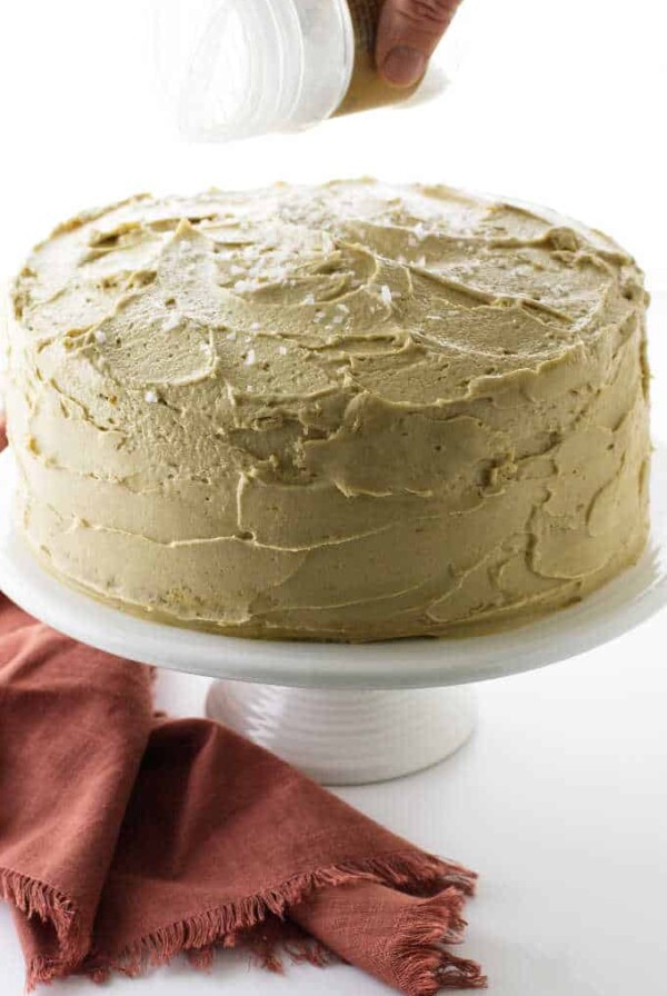 Cake on pedestal with salt being sprinkled on top.