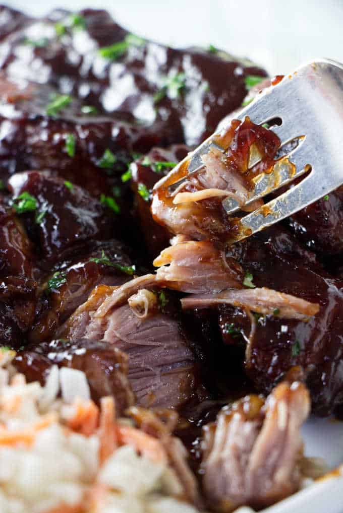 Close up of a country style pork rib being broken up with a fork.