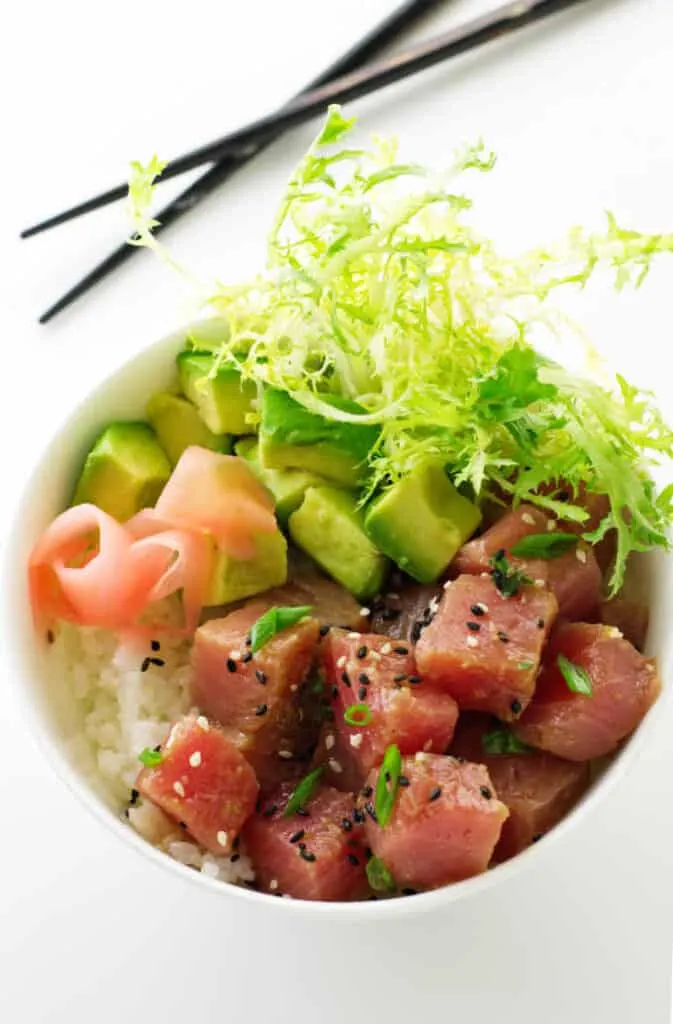 Tuna poke, avocado, sushi rice, salad greens in a bowl.
