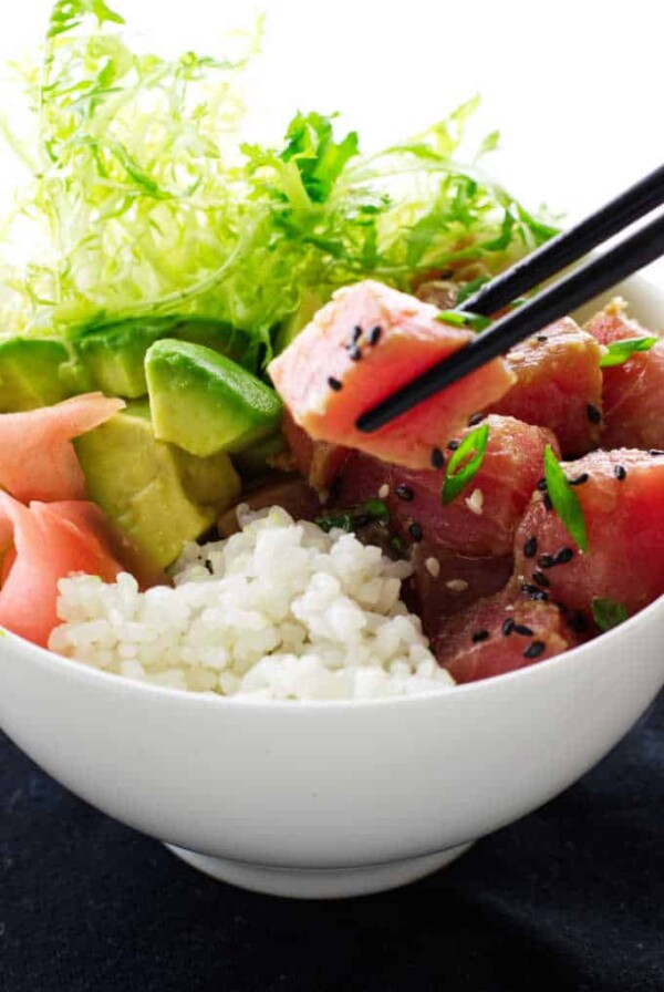 Bowl of tuna poké, chopsticks, avocado, rice and ginger