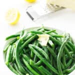 a bowl of steamed green beans with lemon, butter and parmesan cheese