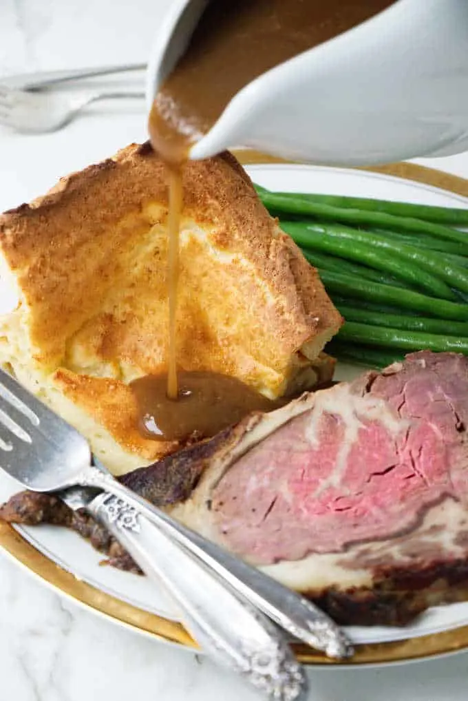 Yorkshire Pudding with a gravy pour, slice of beef and green beans