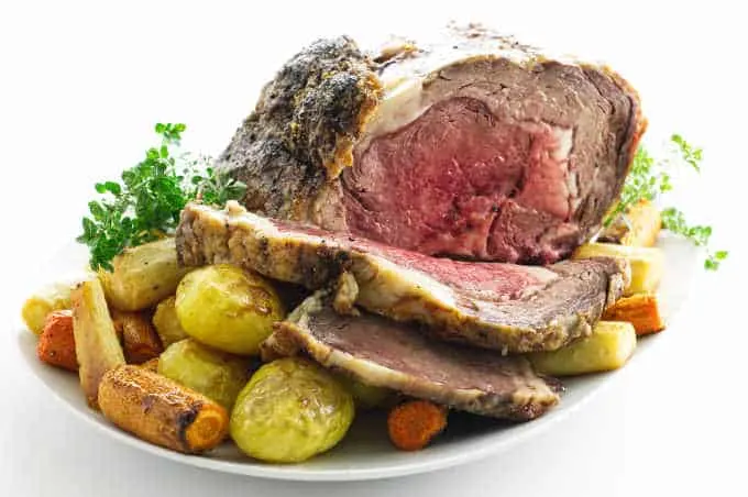 Sliced rib roast on platter with roasted vegetables