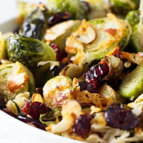 A bowl of roasted Brussels sprouts with parmesan, cranberries, and almonds