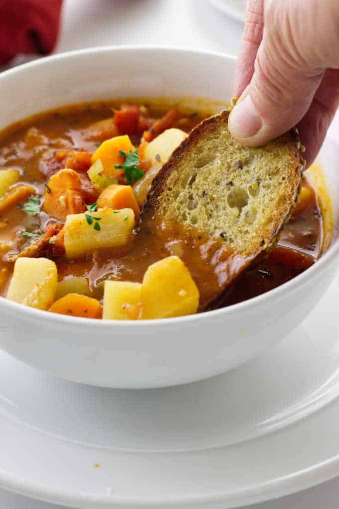 bowl of chowder with bread being dipped