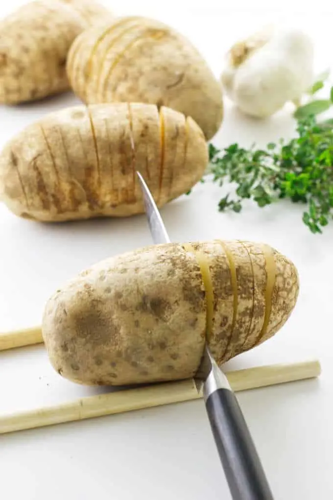 Large potatoes being prepared/sliced for hasselback potatoes