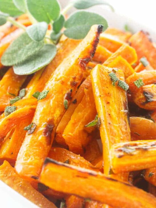 Close up photo of roasted carrots, garnished with fresh sage