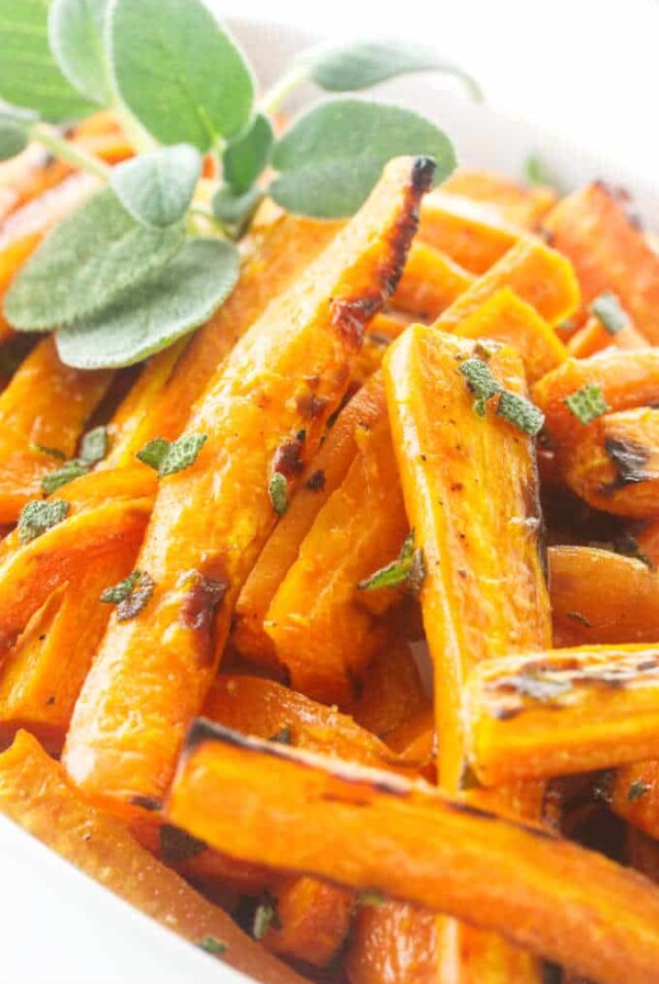 Close up photo of roasted carrots, garnished with fresh sage