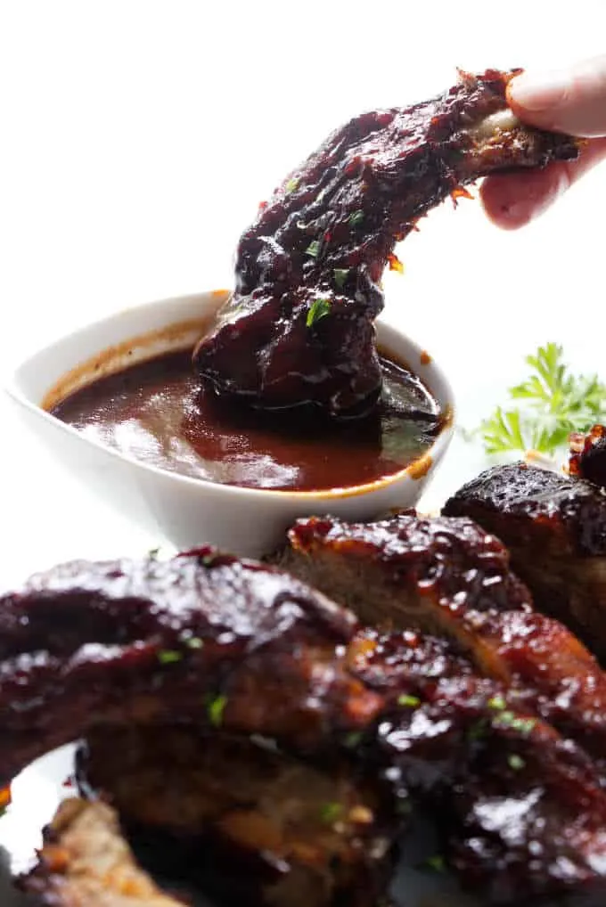 Dipping a baby back rib in barbecue sauce.