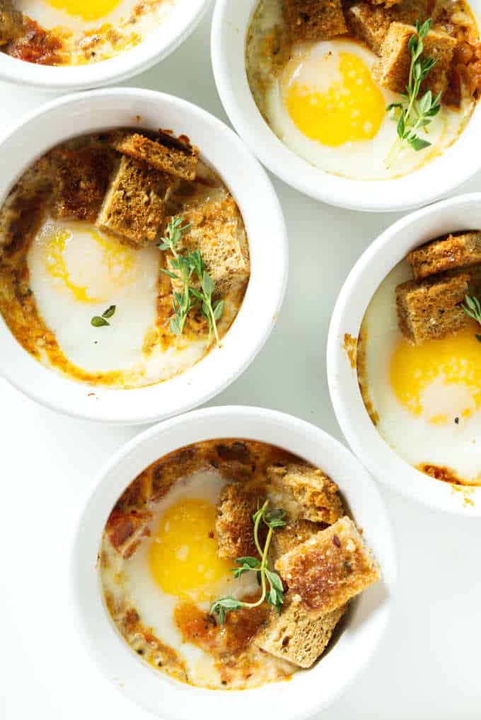 Overhead shot of ramekins with baked eggs and tomato