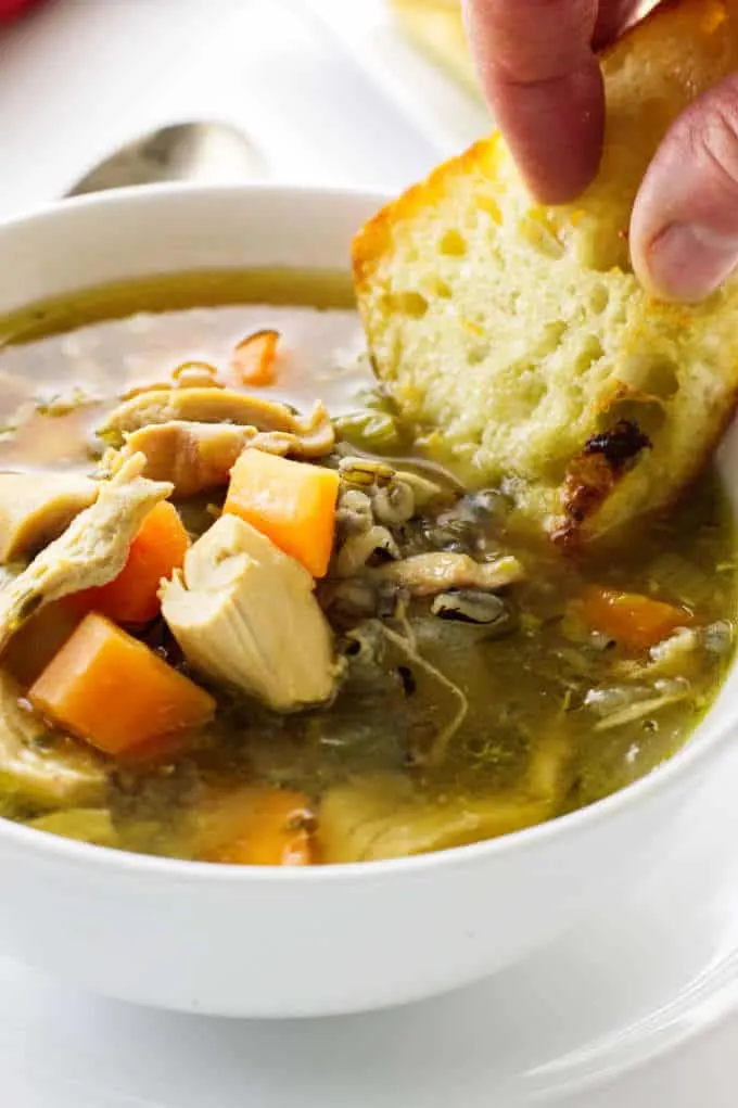 Dunking bread into a bowl of chicken soup with wild rice.