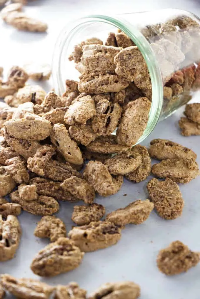 Cinnamon sugar candied pecans spilling out of a jar.