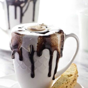 A cup of homemade hot chocolate with chocolate sauce drizzling down the side of the cup.