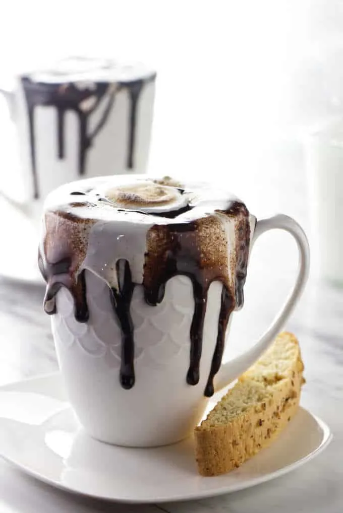 A cup of homemade hot chocolate with chocolate sauce drizzling down the side of the cup.