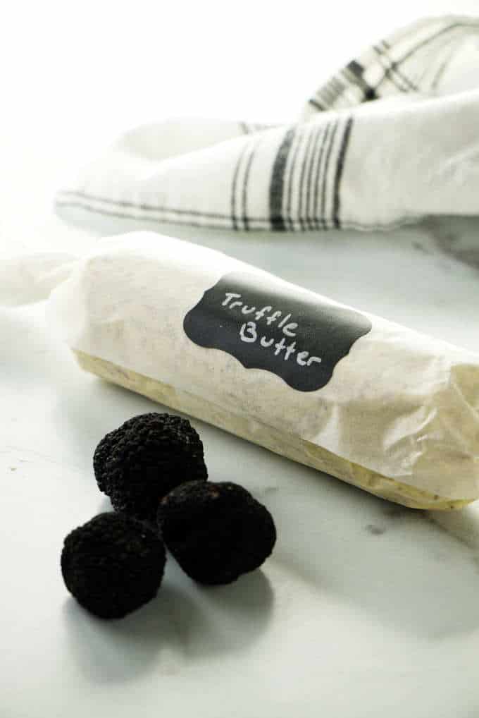 Three black truffles and a wrapped log of truffle butter.