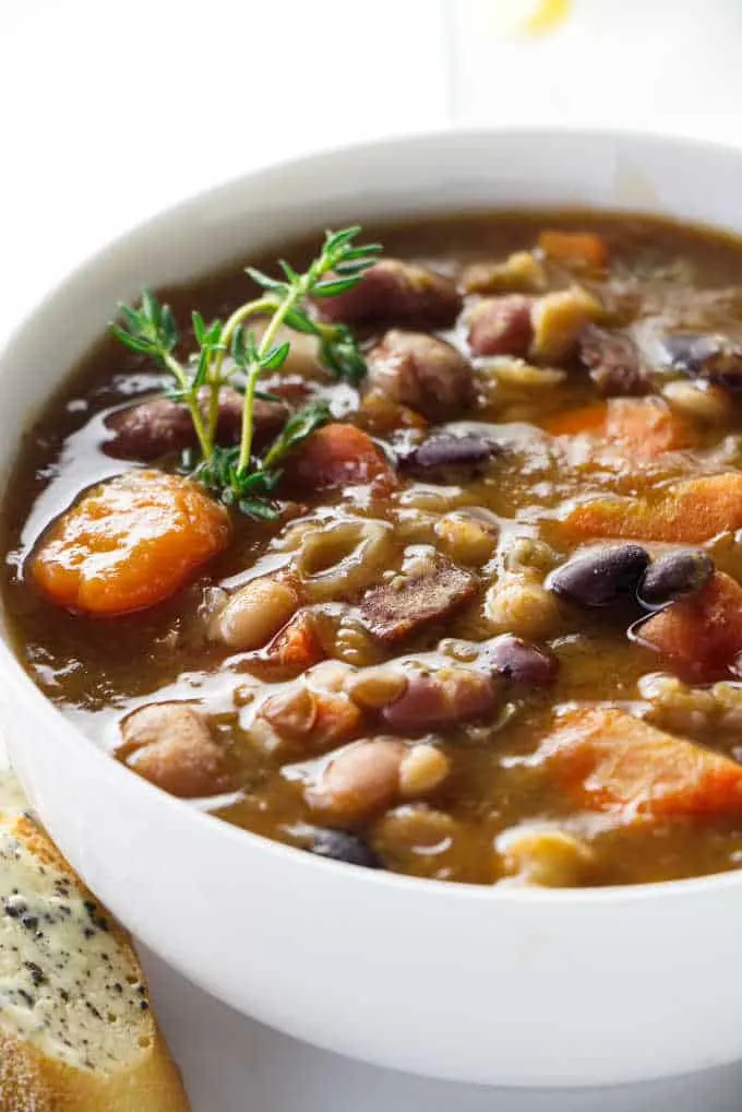 A bowl of 15 bean soup with a glass of water in the background.