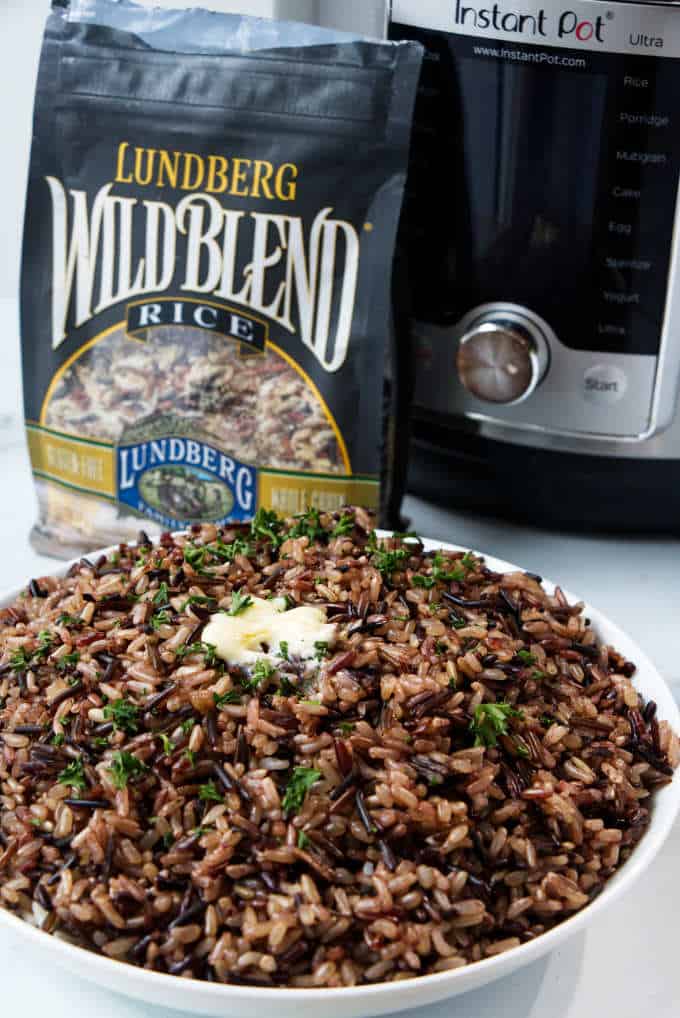 A bowl of wild blend rice with a bag of Lundberg wild rice blend and an instant pot in the background.