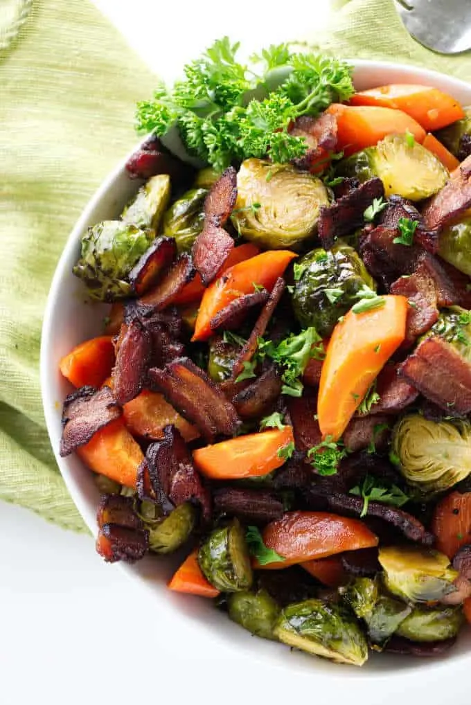 Roasted Brussels Sprouts with carrots and bacon in a bowl.