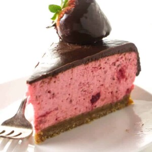 A slice of no-bake strawberry cheesecake covered in chocolate.