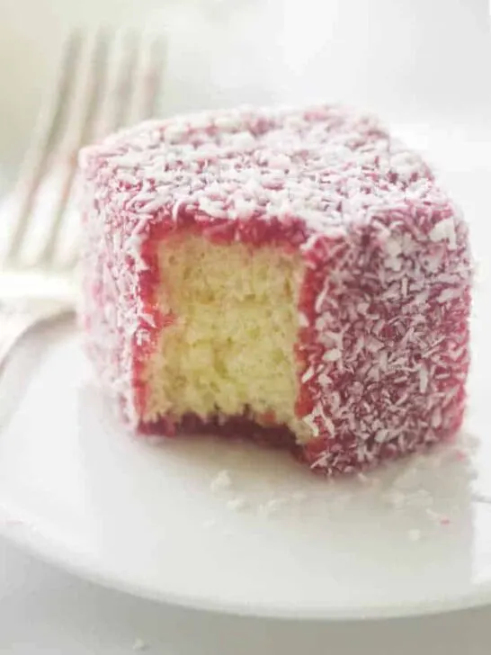 close up of a serving of raspberry lamington on a plate with fork