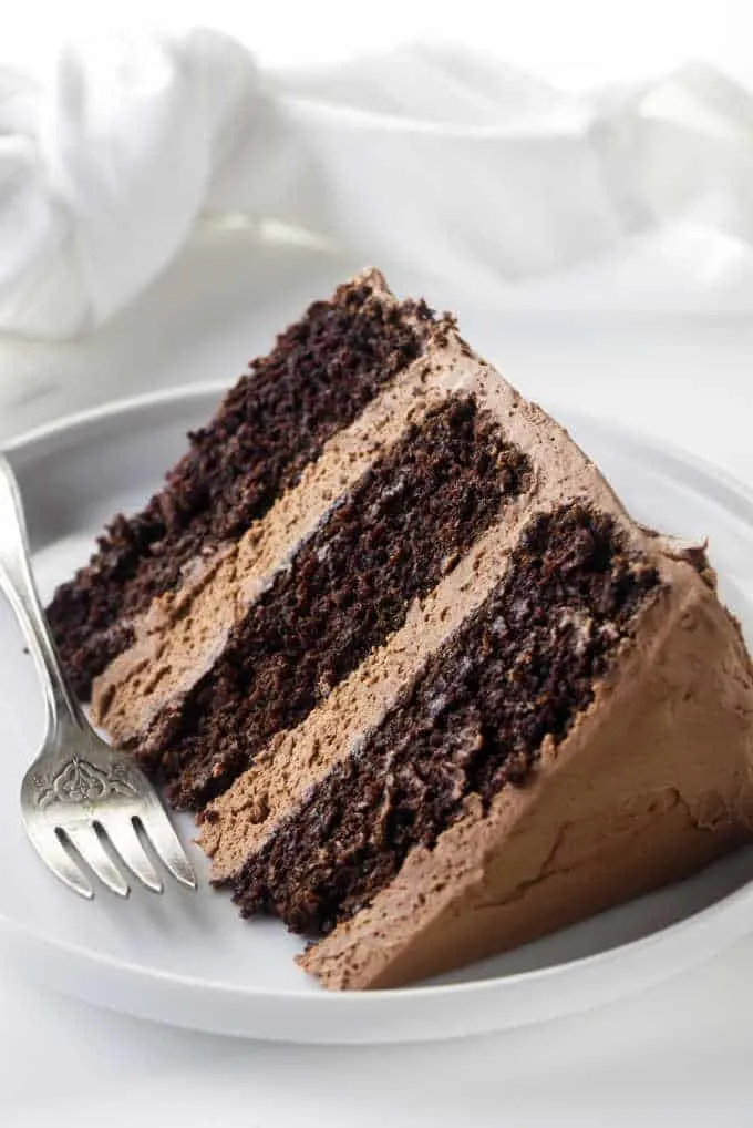 A slice of chocolate cake with chocolate buttercream frosting.