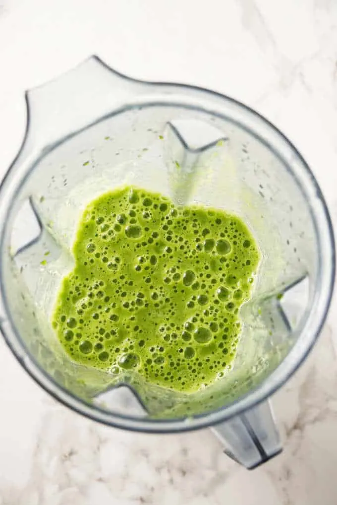 A blender container with a freshly made green power smoothie.