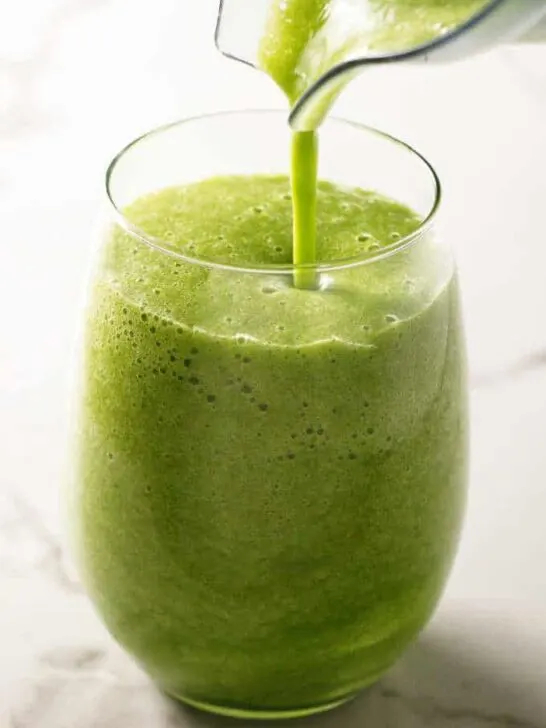 Pouring a green smoothie into a glass.