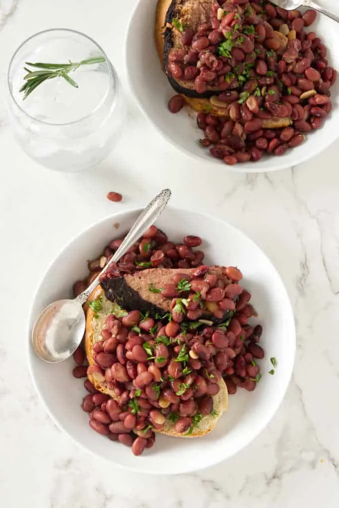 Two servings of red beans and ham in shallow bowls.