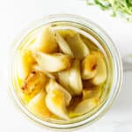 Roasted garlic in a jar with olive oil.