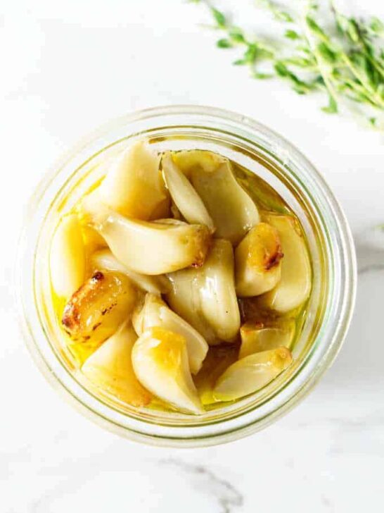 Roasted garlic in a jar with olive oil.