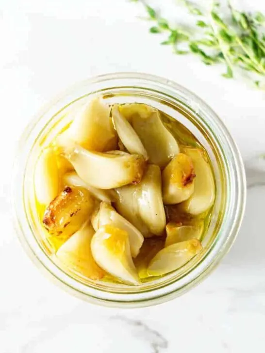 Roasted garlic in a jar with olive oil.