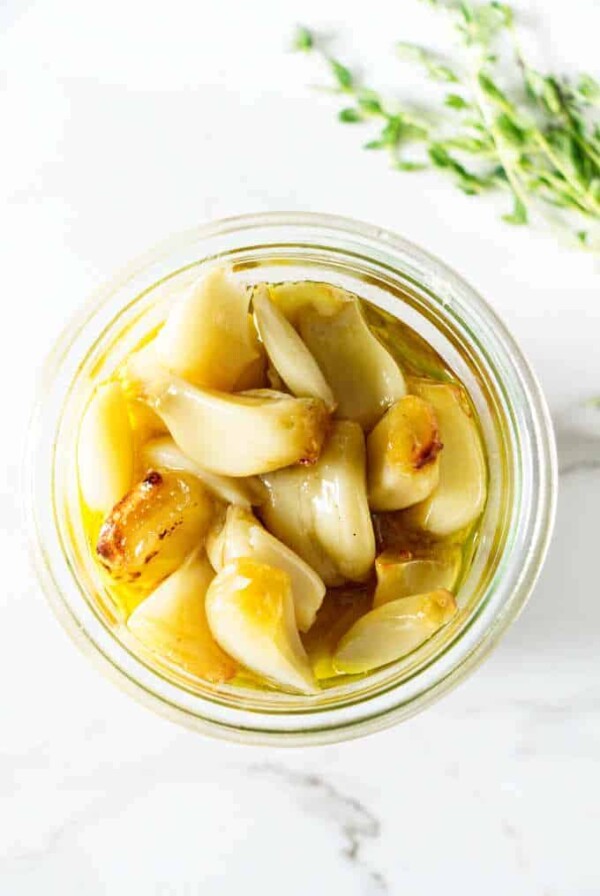 Roasted garlic in a jar with olive oil.