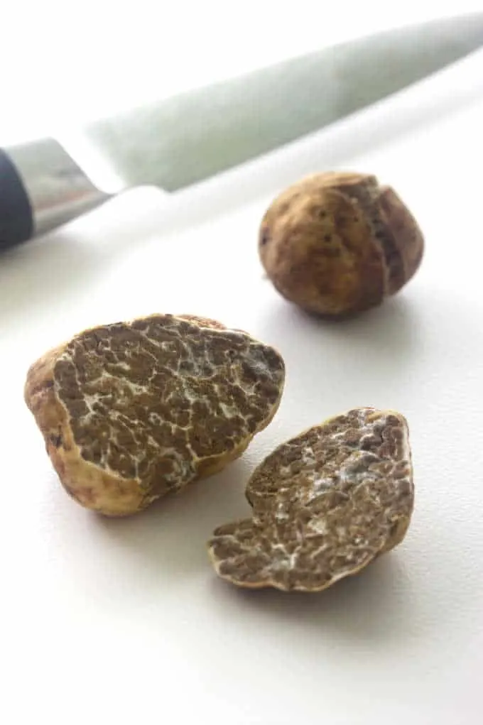Oregon white truffle cut in half, small whole truffle, knife in background